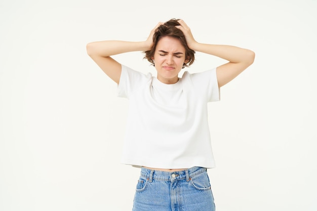 Free photo portrait of woman in panic grabs her head feeling troubled has big problem stands anxious against