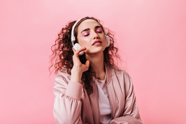 Портрет женщины в розовом наряде, наслаждающейся музыкой в наушниках