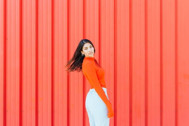 Portrait of woman posing against red corrugated metallic backdrop