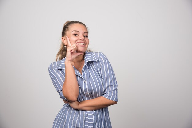 Portrait of woman posing happily on gray wall.