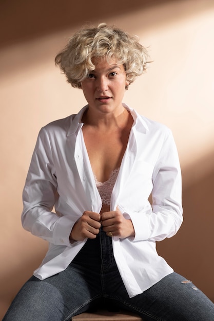 Портрет женщины, позирующей в белой рубашке и показывающей бюстгальтер