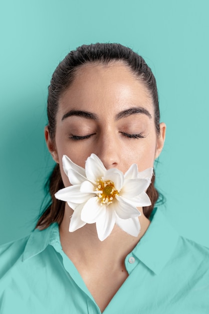 Foto gratuita ritratto della donna che posa con la bocca della copertura del fiore