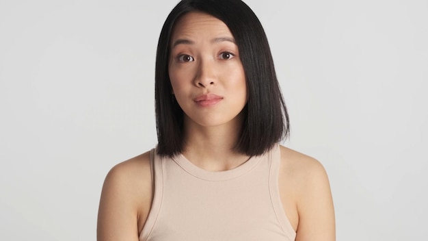 Free photo portrait of woman raising eyebrows looking at camera over white background face expression