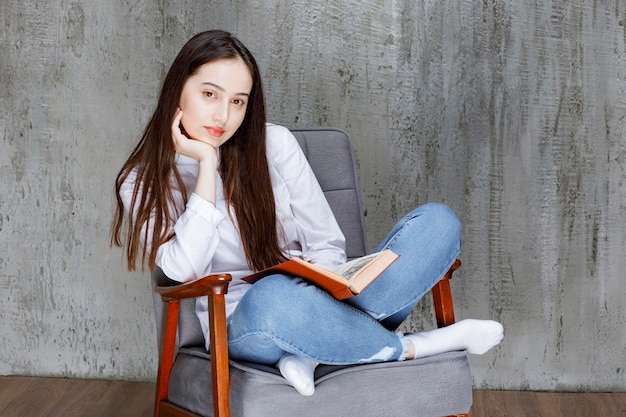 Free photo portrait of woman reading book while sitting on armchair. high quality photo