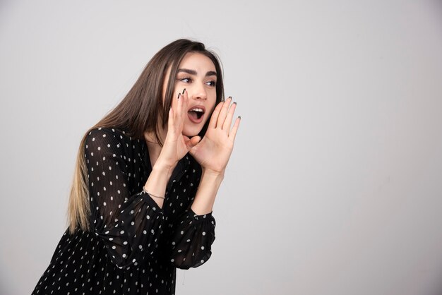 Portrait of woman screaming on gray.