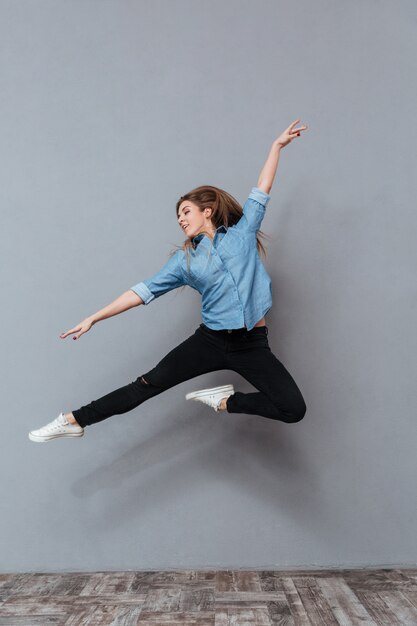 Portrait of woman in shirt jumping in studio
