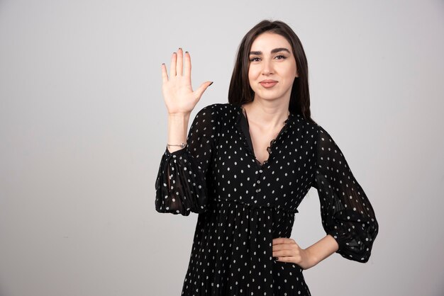 Portrait of woman showing her hand on gray.