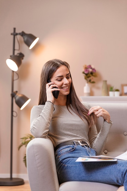 Portrait of woman sitting on couch and talking on phone