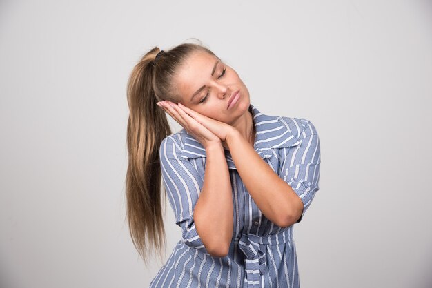 Portrait of woman sleeping on gray wall.