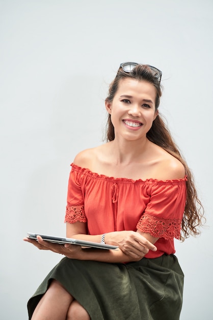 Ritratto della donna che sorride alla macchina fotografica che giudica il suo cuscinetto digitale messo