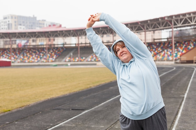 Free photo portrait woman at stadium stretching