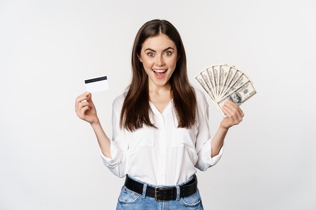 현금과 신용 카드, 돈, 소액 신용 및 대출의 개념으로 서 있는 여성의 초상화, 행복한 배경 위에 서 있는