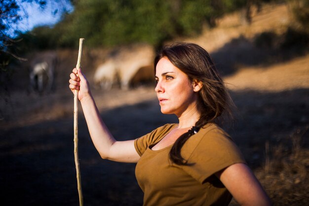 Portrait of woman standing with stick in the field