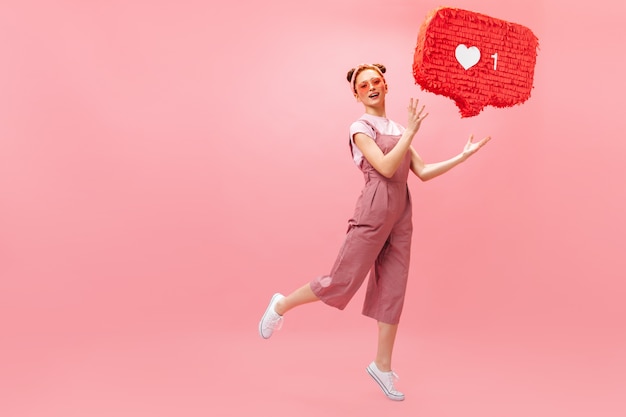 Free photo portrait of woman in sunglasses and pink outfit holding like sign and looking at camera with perplexity.