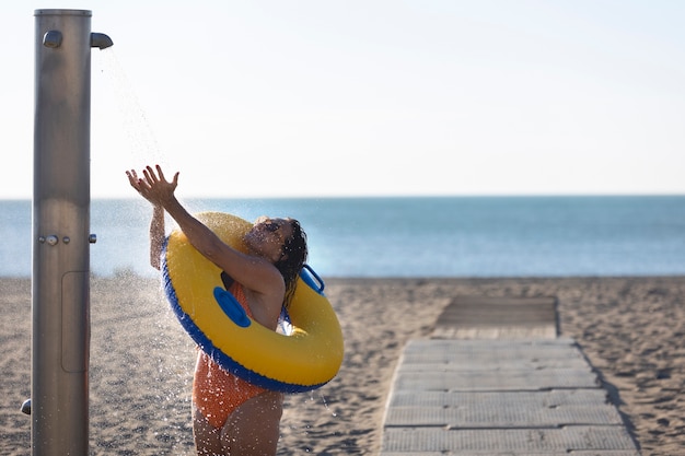 Foto gratuita ritratto di donna che fa la doccia sulla spiaggia