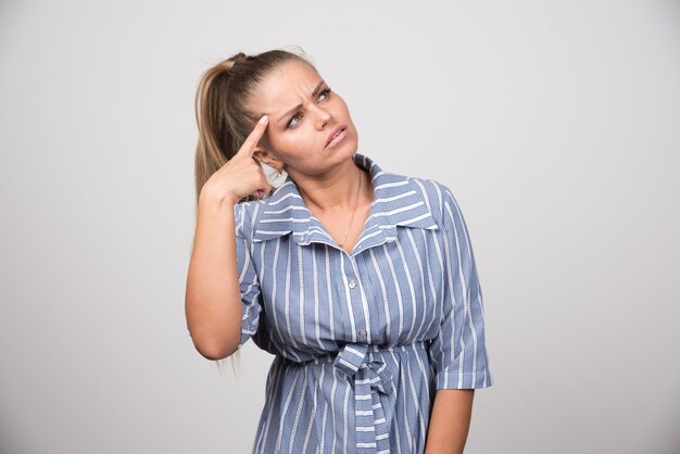 Portrait of woman thinking on gray wall.