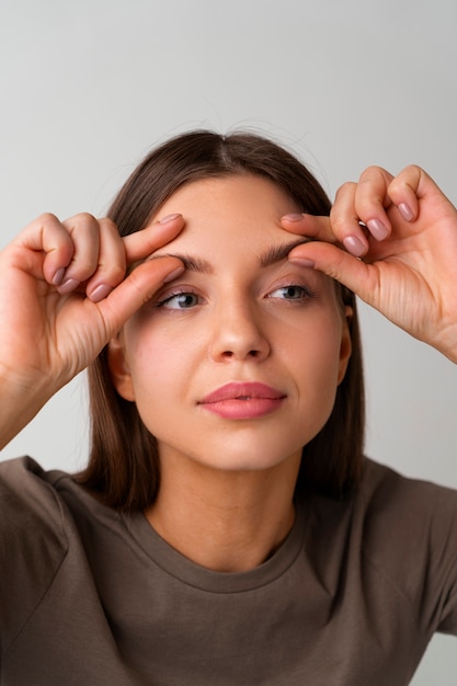 Free photo portrait of woman trying facial yoga massage to stay young