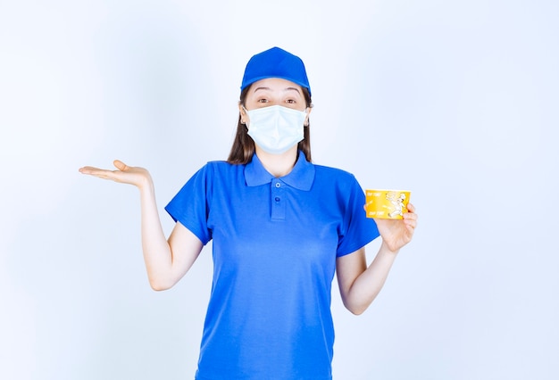 Portrait of woman in uniform and medical mask holding plastic cup