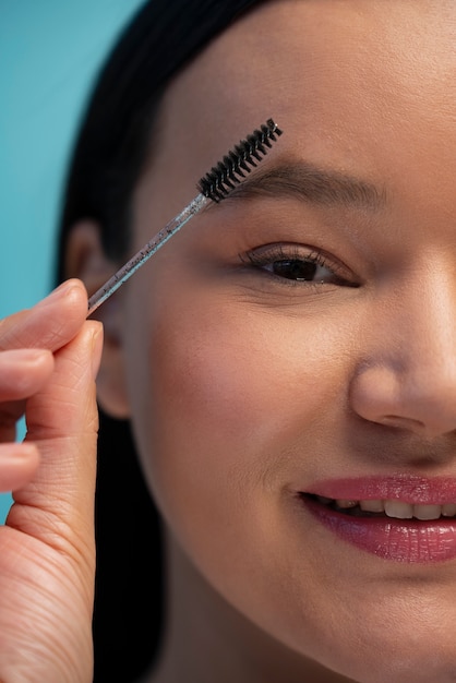 Free photo portrait of woman using eyebrow brush