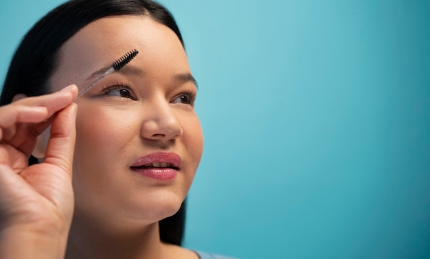 Free photo portrait of woman using eyebrow brush