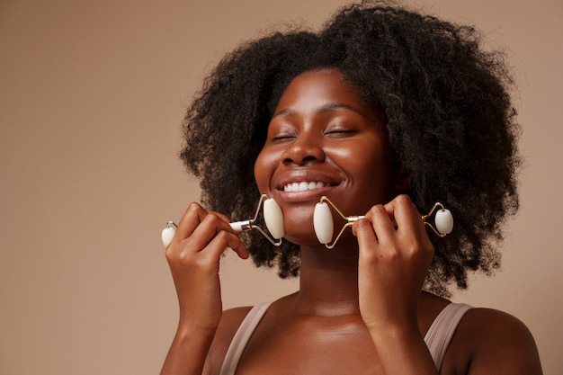 Portrait of woman using face roller for beauty