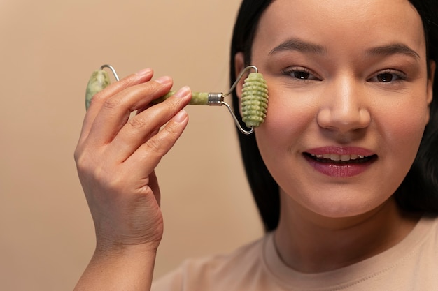 Free photo portrait of woman using jade roller on her face