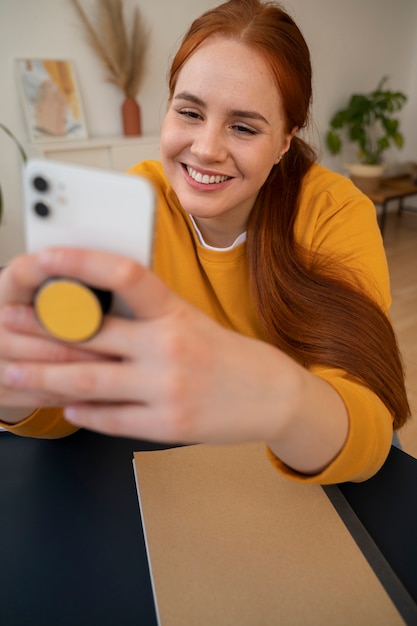 Portrait of woman using smartphone at home with pop socket