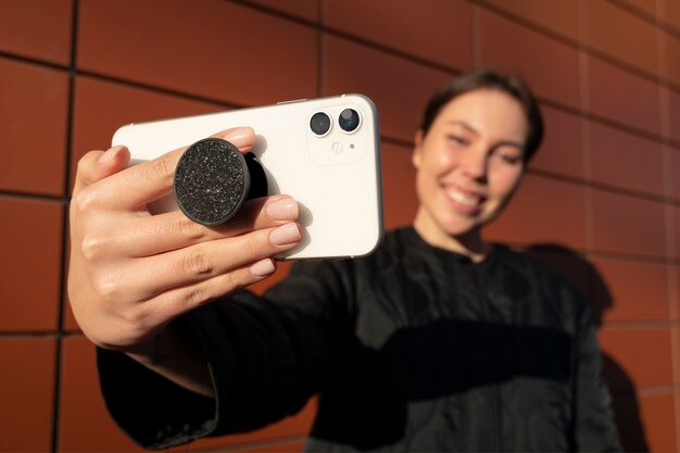 Portrait of woman using smartphone with pop socket outdoors