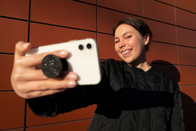 Portrait of woman using smartphone with pop socket outdoors