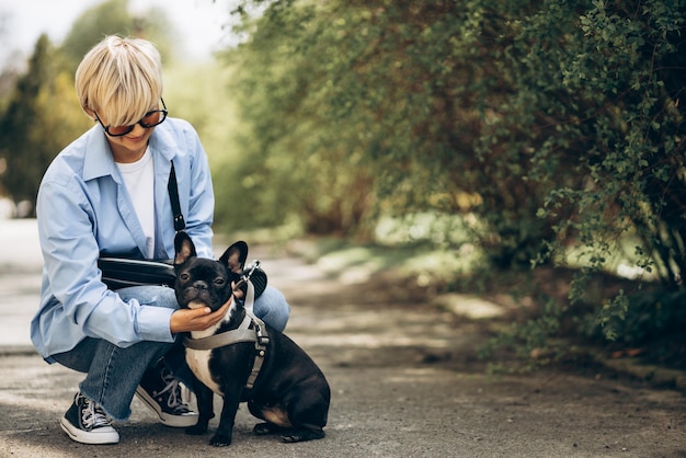 Portrait of woman walking in park with her pet french bulldog