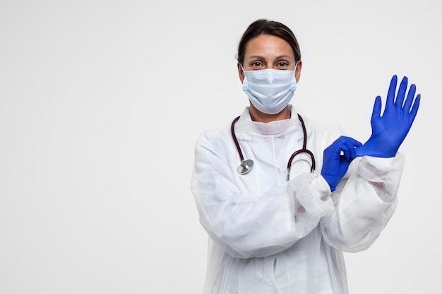 Free photo portrait of woman wearing medical gown and putting on gloves