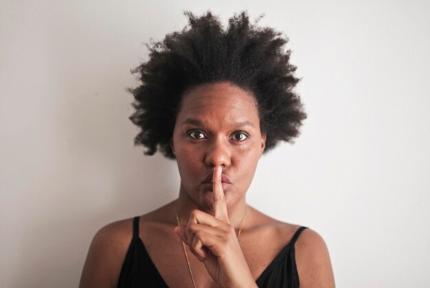 portrait of woman while making the gesture of silence