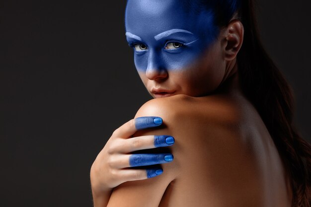 Portrait of a woman who is posing covered with blue paint