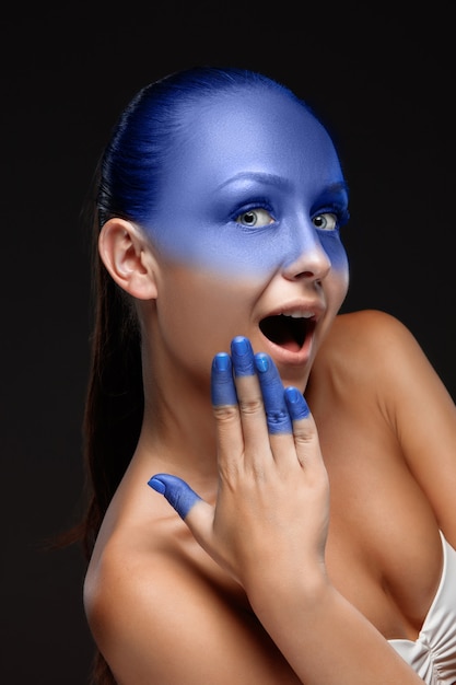 Portrait of a woman who is posing covered with blue paint