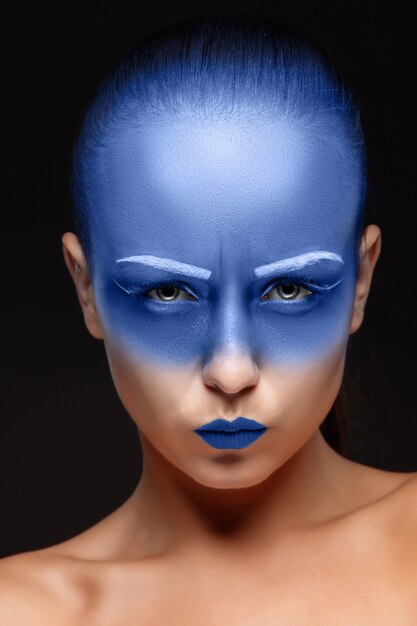 Portrait of a woman who is posing covered with blue paint