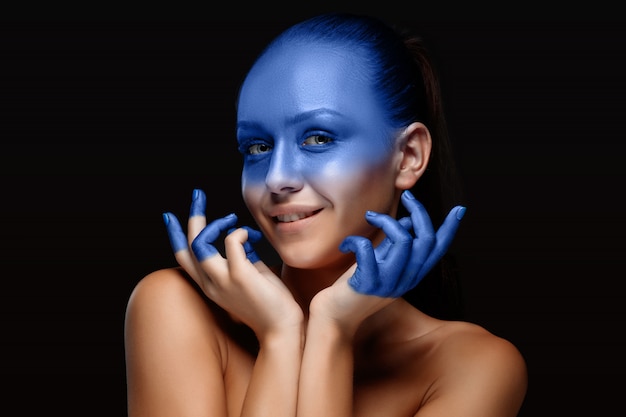 Portrait of a woman who is posing covered with blue paint