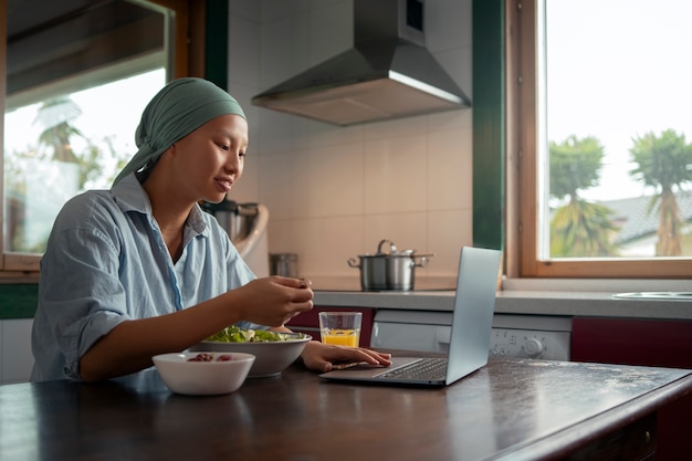 Портрет женщины с раком, едящей салат дома