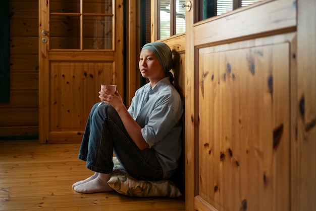 Free photo portrait of woman with cancer having a drink at home