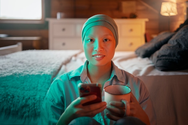 Free photo portrait of woman with cancer using her smartphone at home