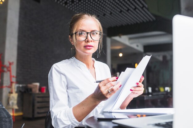 Portrait of a woman with document looking at camera