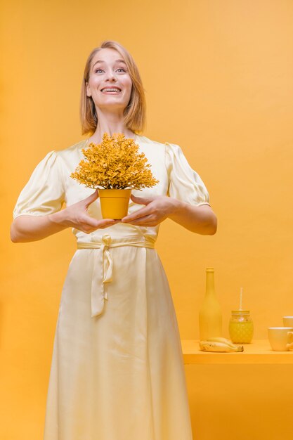 Portrait of woman with a flower pot in a yellow scene