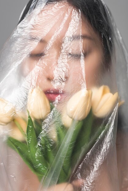 Portrait of woman with flowers being covered in plastic