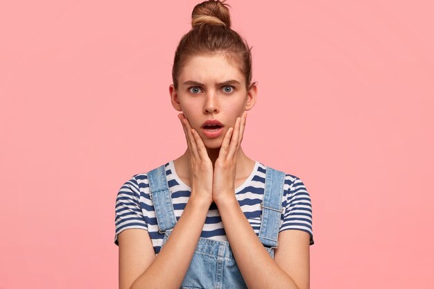 Portrait of woman with hair in a bun and wearing denim overalls