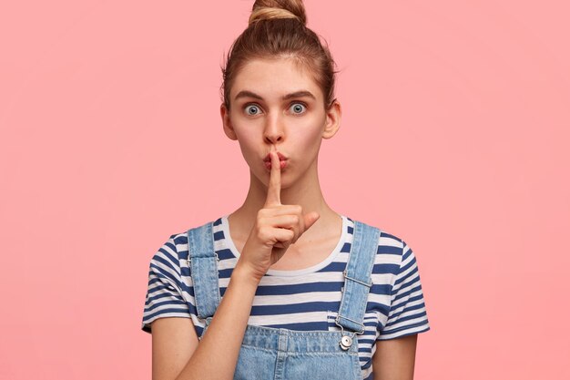 Portrait of woman with hair in a bun and wearing denim overalls