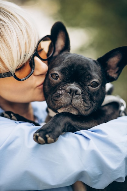 Portrait of woman with her pet french bulldog in a park