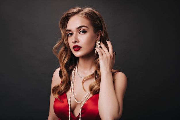 Free photo portrait of woman with red lips looks into camera on black background