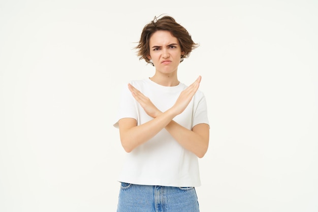 Foto gratuita il ritratto di una donna dal volto serio mostra un gesto di arresto incrociato che proibisce la presenza di qualcosa di brutto