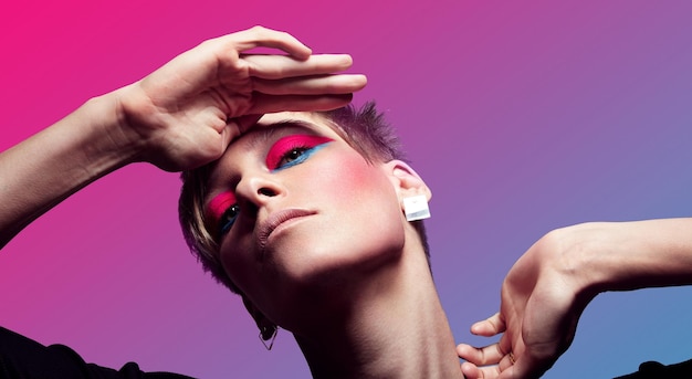 Portrait of woman with a short hair and neon makup on a gradient background