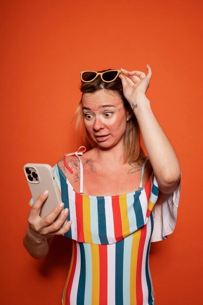 Portrait of woman with sunburn marks on skin looking at smartphone