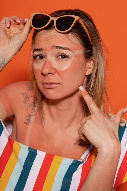 Portrait of woman with sunburn marks on skin and sunglasses